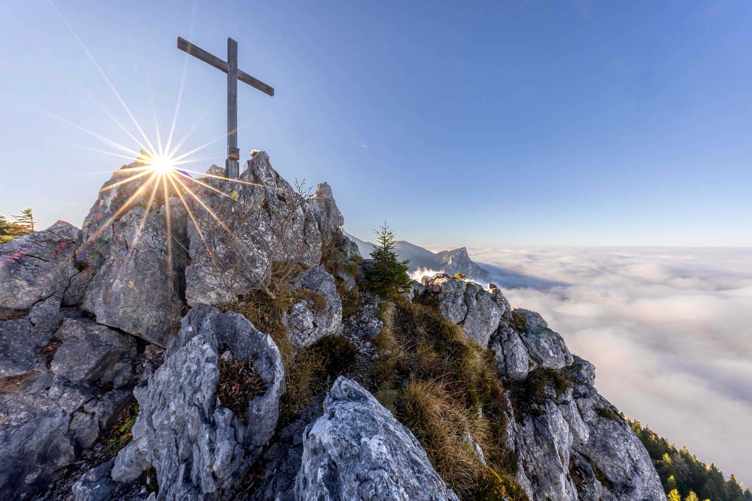 Gipfelkreuz Friedenrath mit Sonne und Wolkendecke